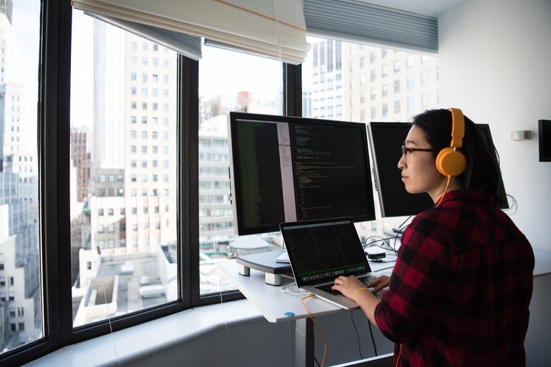Woman coding on a computer in front of a window_AutoRABIT