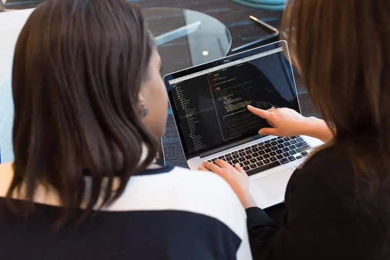Moving-Beyond-Clicks-Not-Code-in-Salesforce-3 Two people coding on a computer_AutoRABIT