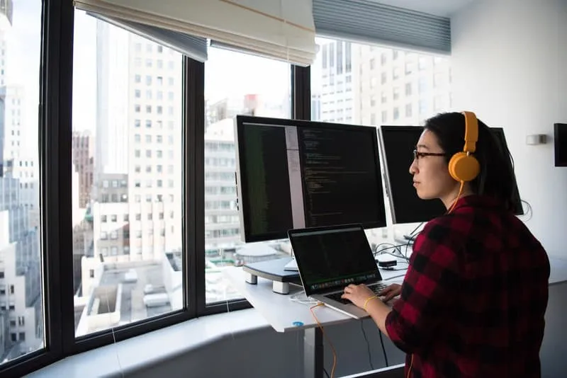 Do-I-Need-a-Salesforce-Release-M Woman coding on a computer in front of a window_AutoRABIT